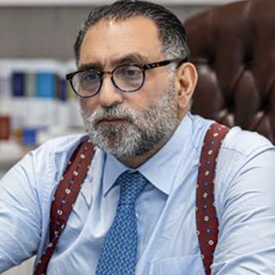 Profile pic of Azmi Bishara showing a serious man in glasses sate at a desk.