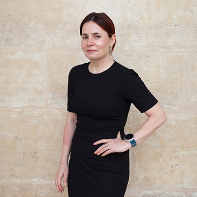 Author profile pic of Alexandra Prokopenko showing a woman dressed all in black in slight profile with a hand on her hip.